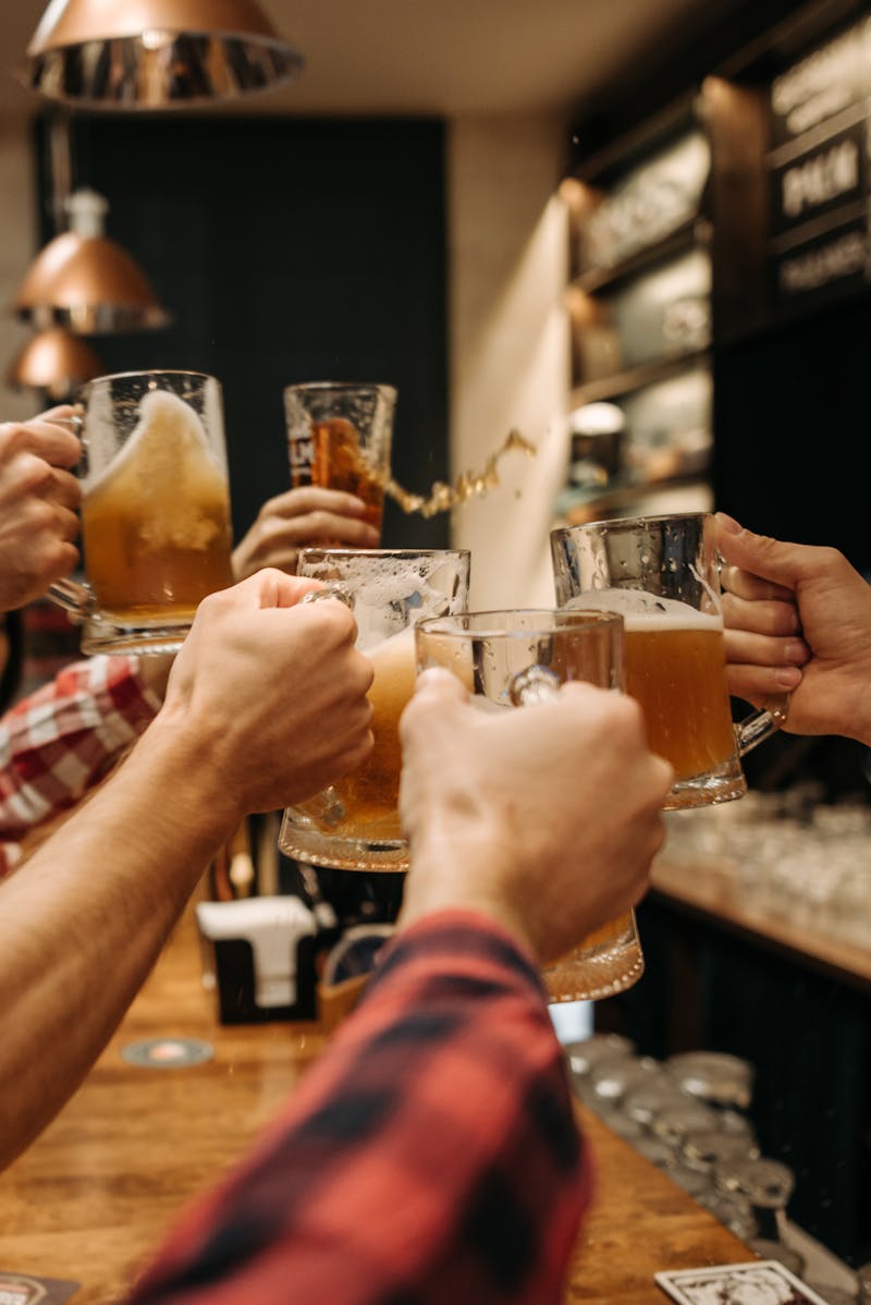 Friends toasting with beer mugs in a warm pub. — Photo by Pavel Danilyuk on Pexels